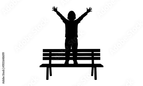 Silhouette of a happy child standing on a park bench with arms raised