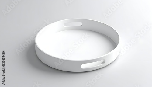 A minimalist, round, white tray with handles, sitting on a plain gray surface