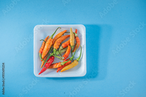 Fresh Orange and Red Chili Peppers on Blue Background