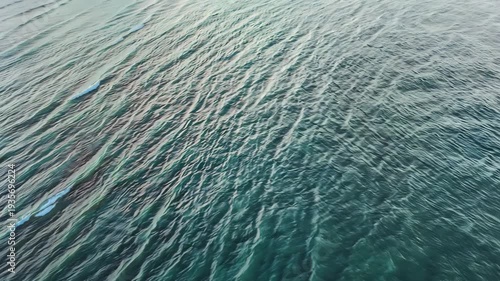 Water surface with gentle ripples reflecting light, showcasing a serene aquatic environment with varying shades of blue and green in a coastal setting