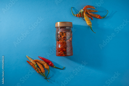 Chili Flakes and Fresh Peppers on Blue Background