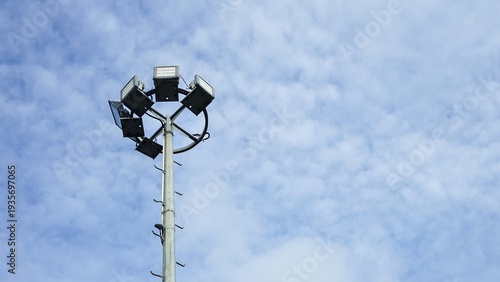 Fotografija Stadium floodlight pole against a bright blue cloudy sky.