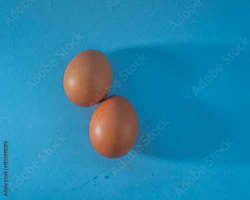 Two Brown Eggs on Blue Background