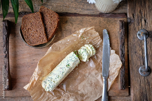 Top view of homemade herb butter with chives on parchment paper.