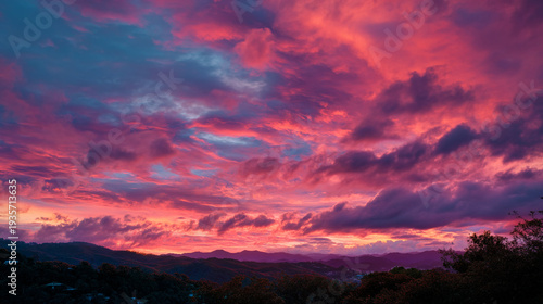 A vibrant pink and purple sunset with clouds over a mountainous landscape