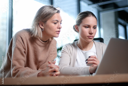 Two women are looking at a laptop together
