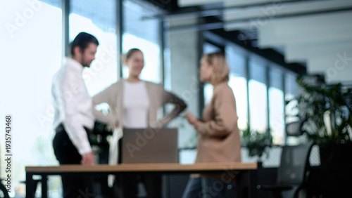 Three people are standing around a table in a room