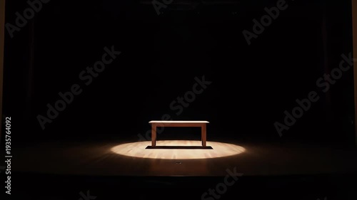 A solitary table illuminated in a spotlight against a dark backdrop.