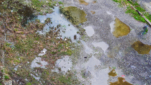 Canvas Print Aerial view of muddy ground with puddles and scattered debris in urban area