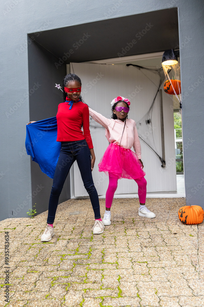 Obraz premium African American preteen and child girls posing at front door wearing capes, tutu, pumpkin, web