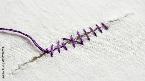 Close-up of a neat purple whipstitch mending a white fabric seam, showcasing traditional hand sewing and textile repair techniques