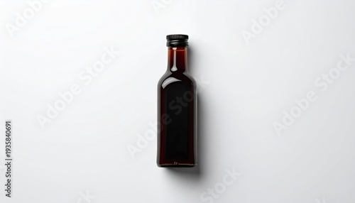 Small Dark Brown Glass Bottle with Black Lid on a Plain White Surface