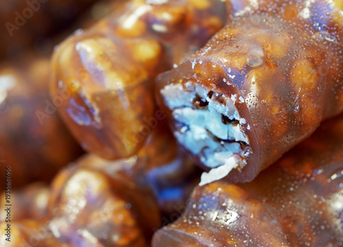 Macro shot of traditional Turkish Cevizli Sucuk (Churchkhela), featuring whole walnuts coated in a thick, glossy grape molasses jelly