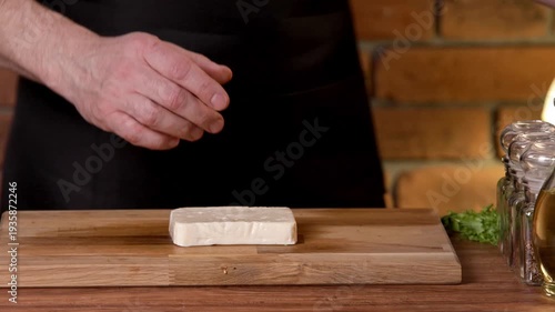 A chef cuts white feta cheese with a knife on a cutting board.