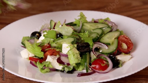 A chef serves salad from a bowl onto a white plate.