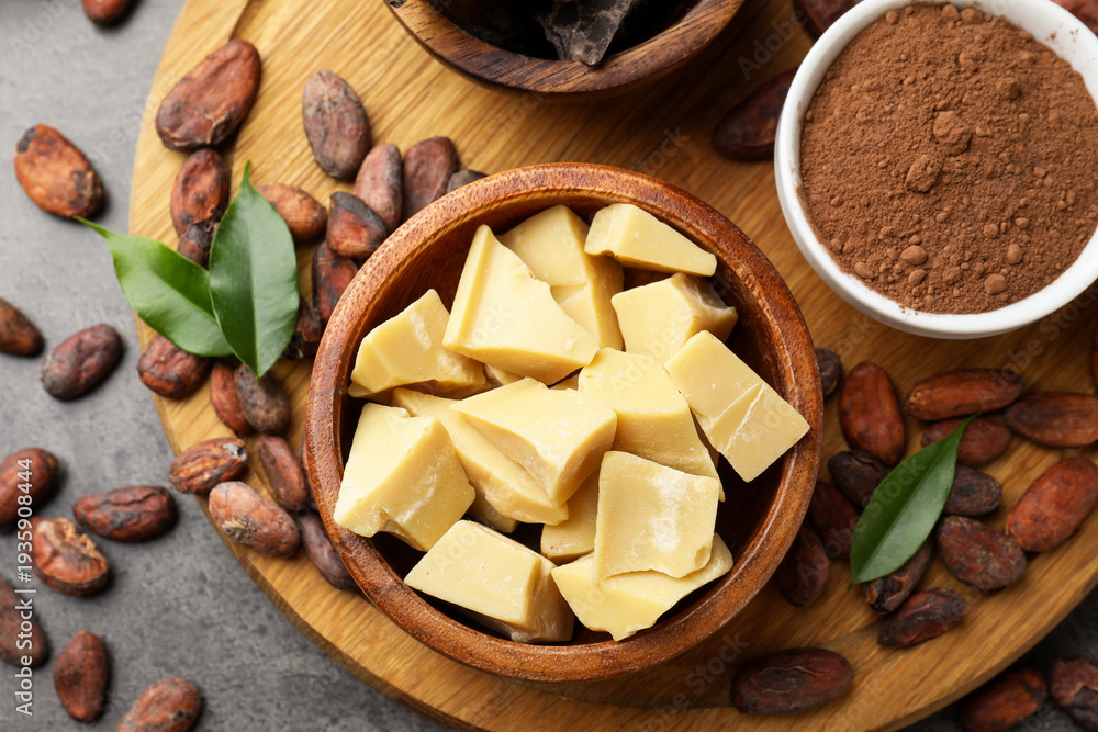 Obraz premium Organic cocoa butter, beans, powder and green leaves on grey table, top view