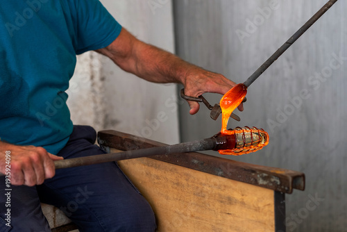 Foto Murano glassmaker working molten glass, blowpipe, metal jacks, workshop furnace,