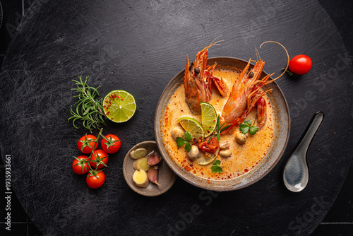 Tom Yam kung Spicy Thai soup with shrimp, seafood, coconut milk and chili pepper in a bowl, top view with copy space