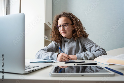 A teenage student is studying on a laptop. Education of children at school takes place in the interior of the home classroom. Online education and training online