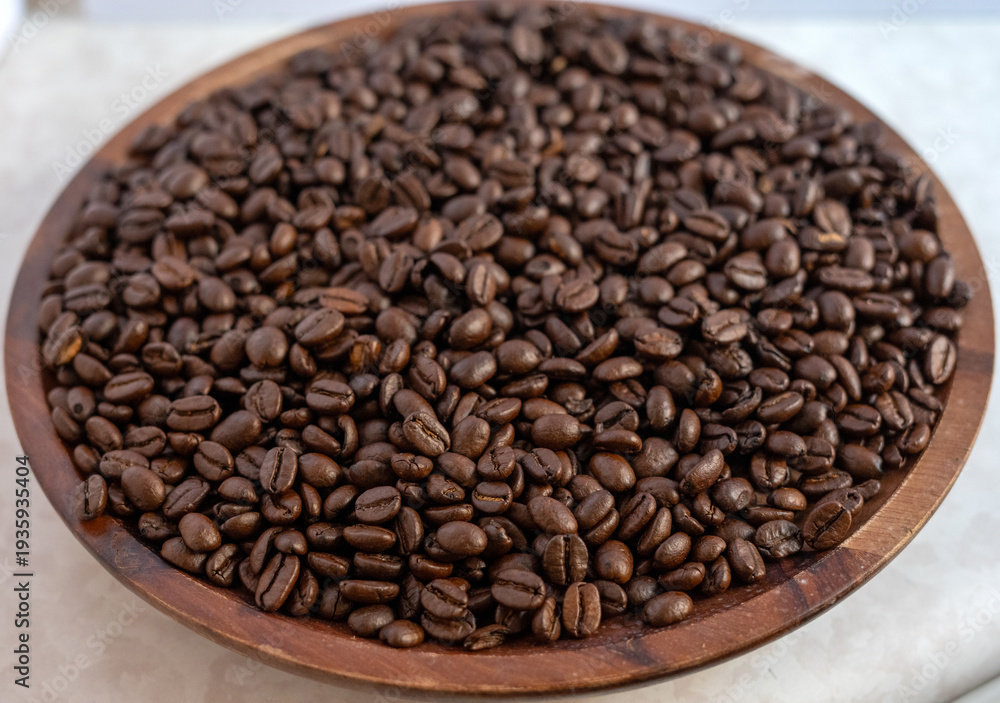 Fototapeta premium Close-up macro of roasted dark coffee beans filling a wooden bowl