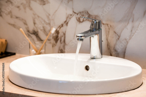 Modern bathroom interior with marble tiles, a sink, and a faucet. Hot water shutdown schedule. Sanitary store concept. Bathroom decor and details.