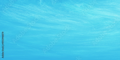 The abstract texture of a clear blue water surface features gentle ripples and turquoise waves reflecting summer light across a clean liquid pool