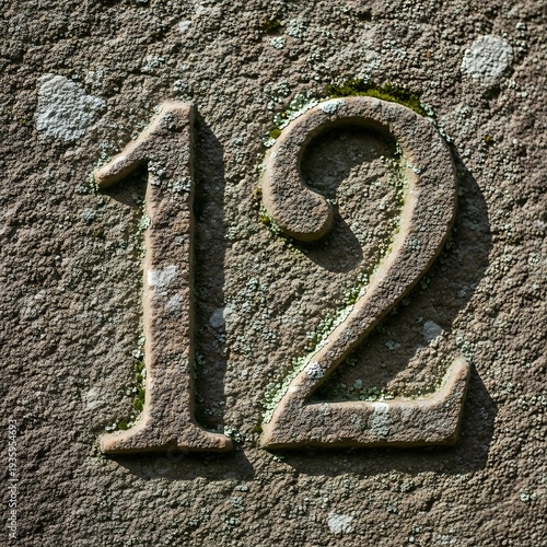 Worn stone engraving displaying the number twelve prominently on a textured surface.