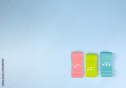 blue background with small bands, tiny resistance loops set against wide azure background, minimalist layout featuring petite resistance bands on expansive blue negative space for promotion