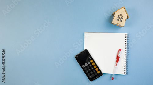mobile device alongside notebook and pen, cell phone calculator coupled with notepad and red pen, smartphone calculator positioned next to notebook with red ink pen indicating lease planning