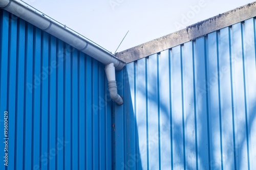 Blue corrugated metal wall with gutter and shadows