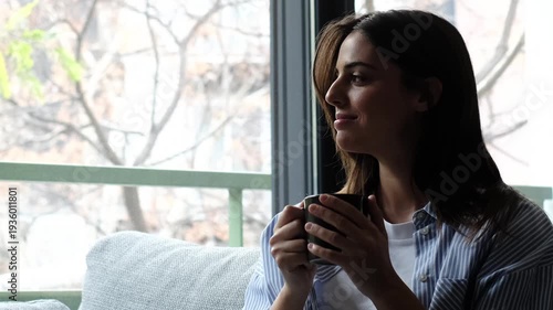 Adult woman relaxing on living room sofa at home, calm and smiling with positive thoughts, single lifestyle moment with mindfulness, wellbeing and mental clarity