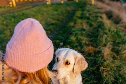 Gentle female, blonde Caucasian, sharing quiet eye contact with golden retriever in sunset light
