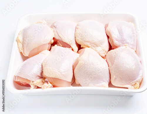 Raw chicken thighs in a foam tray package, white background. AI