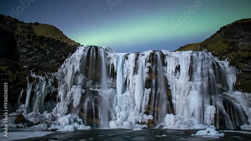 Frozen waterfall cascades under the northern lights amidst a starlit night sky