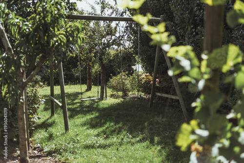 Swing, an outdoor playground for children surrouned by lush greenery outdoor at daytime during summer in a backyard in The Netherlands.
