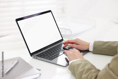Woman working on laptop at white table indoors, closeup