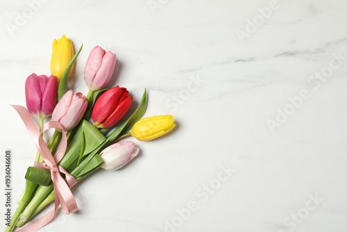 Beautiful colorful tulip flowers on white marble background, top view. Space for text