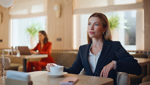 Stylish lady sipping cappuccino in light cafe interior closeup. Confident woman 