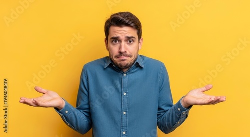 Young man with a confused expression shrugging, hands open, indicating uncertainty on yellow back...