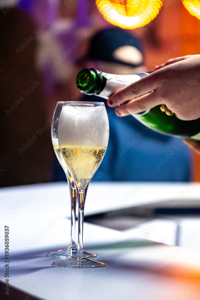 Fototapeta premium Pouring in glasses of french sparkling wine champagne with little bubbles, tasting wine, celebration, wedding or champagne tour with visit of caves, Reims, France