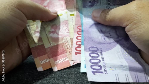 a person counting Indonesian Rupiah banknotes, illustrating concepts represents common financial activities such as salary calculation, budgeting, savings, payments, profit, and expense management