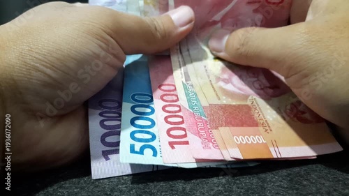 Man counting Indonesian Rupiah money paper bills, cash economy concept