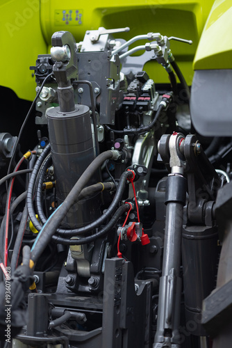 Close up of industrial hydraulic system with metal cylinders, hoses and control valves inside modern agricultural machine. Engineering technology, heavy equipment mechanics and high power machinery