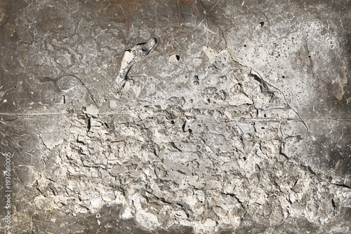 Gray cracked plaster wall texture with peeling paint and rough damaged surface. Abstract grunge background with old cement layer and weathered structure creating distressed urban material backdrop