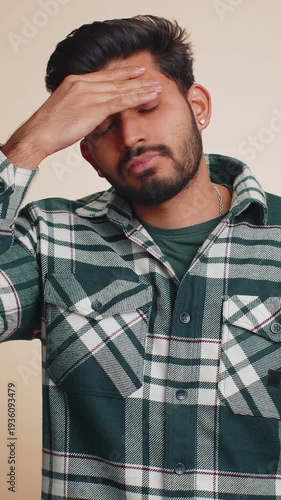 Unhealthy young Indian man coughing covering mouth with hand, feeling sick, allergy or viral infection symptoms, fever pain virus. Handsome bearded Hindu boy isolated alone on beige studio background