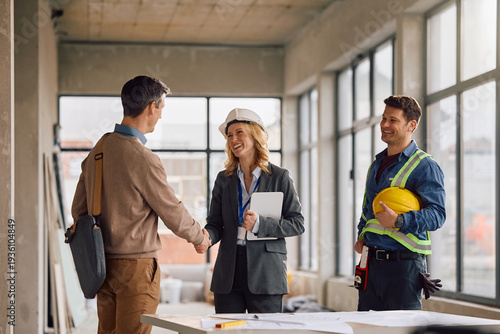 Happy architect greeting her client at construction site.
