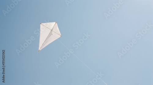 White kite soars gracefully against a clear blue sky on a sunny day