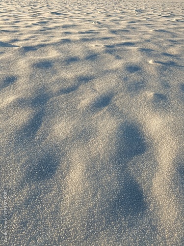 Abstract snow surface texture with ice crystals and soft blue shadows, winter background