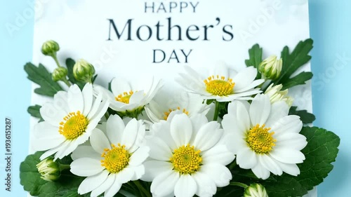 White daisies surround a card wishing Happy Mother's Day on a light blue background.