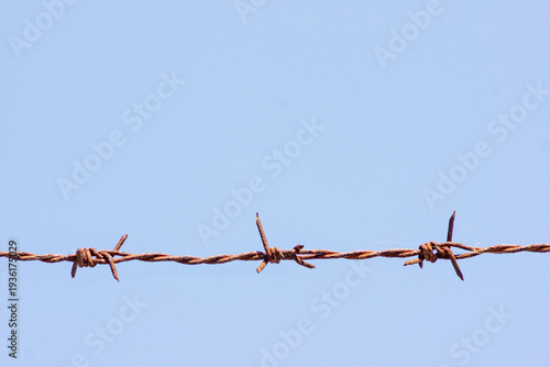 Barbed wire with blue sky as the background.